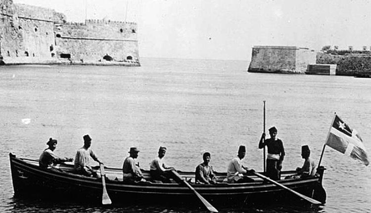 ΦΩΤΟΗΜΕΡΑΣ: Ηράκλειο, 1913. Με βάρκα μπαίνουν στο λιμάνι, διακρίνεται ακόμη η σημαία της Κρητικής Πολιτείας (η Ένωση έγινε τον Δεκέμβριο του 1913) και ο μικρός Κούλες.